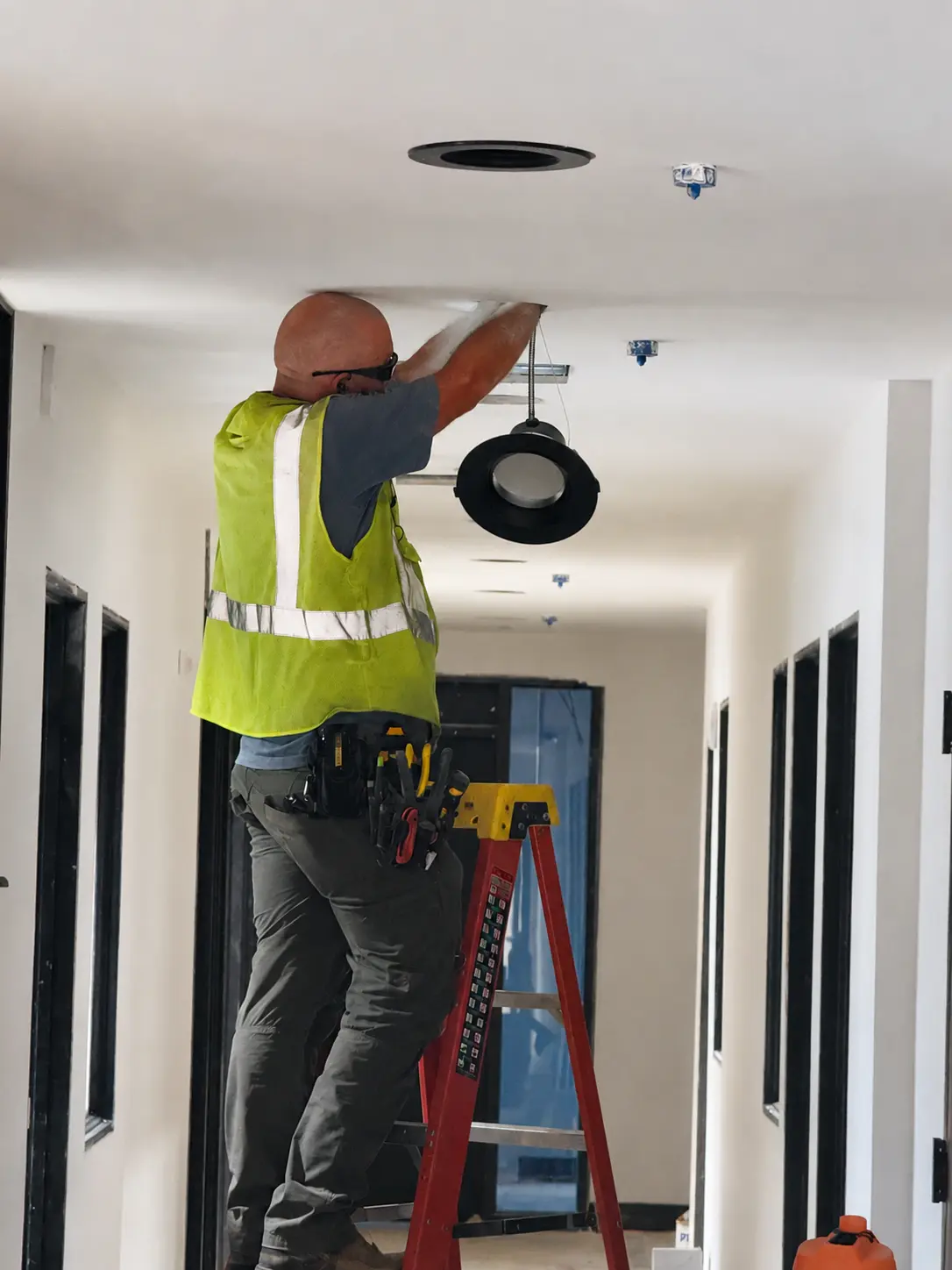 Electrician installing a recessed commercial downlight