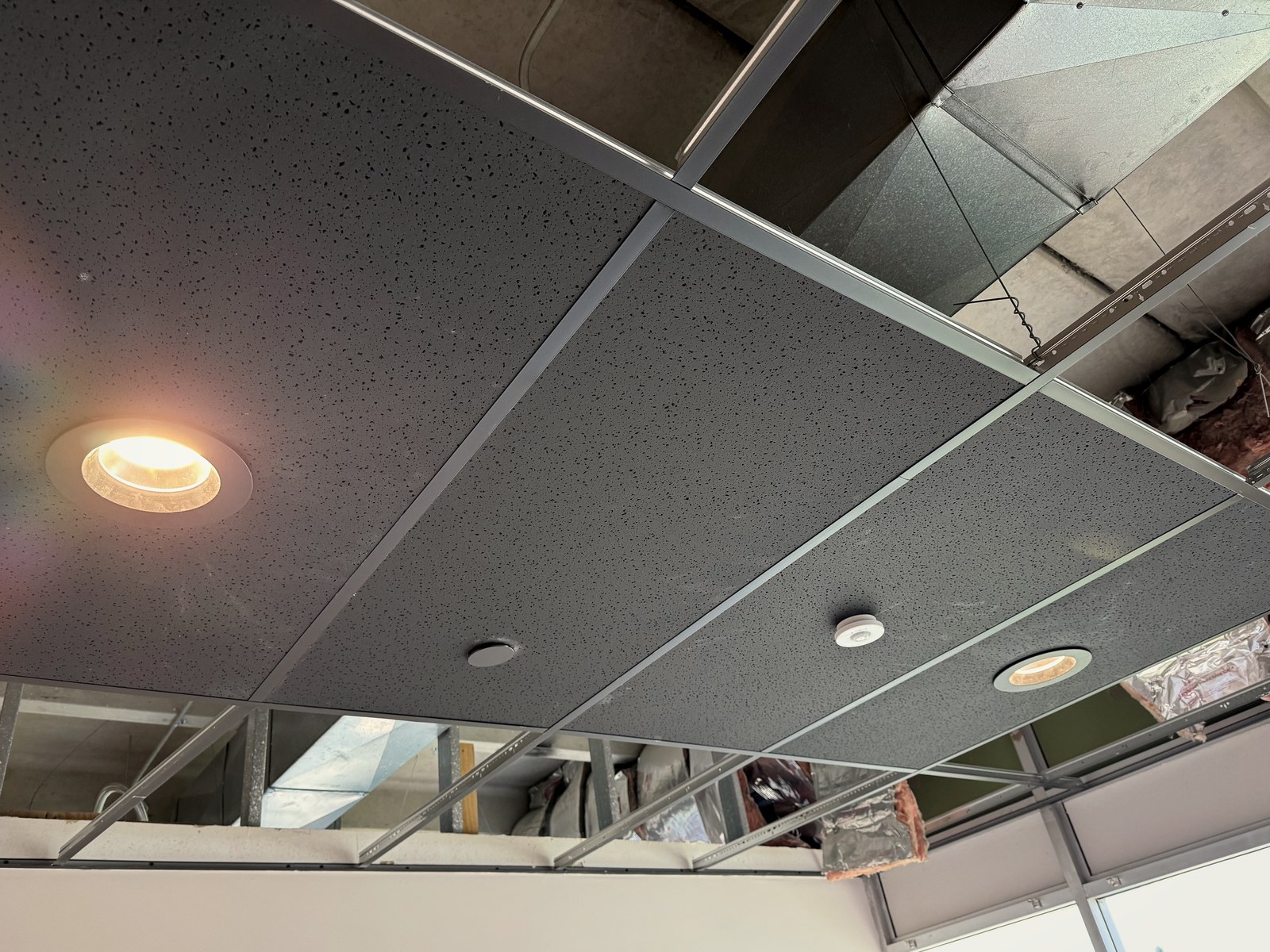Recessed LED downlights and a ceiling occupancy sensor set in acoustic tile