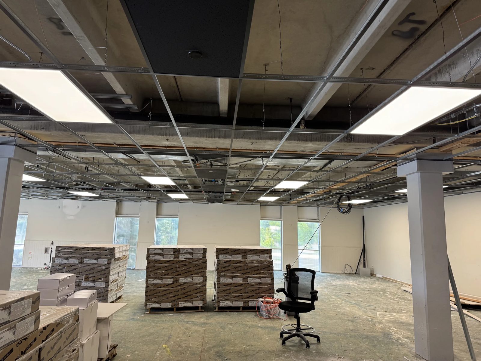Open office area lit by recessed LED fixtures in a new suspended ceiling grid